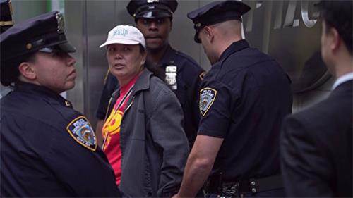 '图3：二零一六年五月十三日，李华红（左二，带白帽者）因为干扰法轮功的活动被纽约警察当场拘捕。（大纪元）'