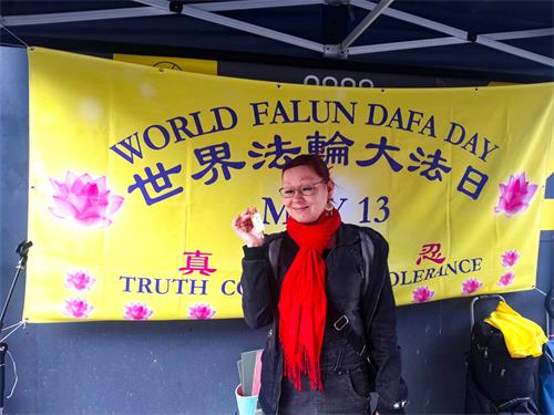 图8：残疾人指导教师T. Pyy女士手拿小莲花，在“世界法轮大法日”横幅前拍照留影