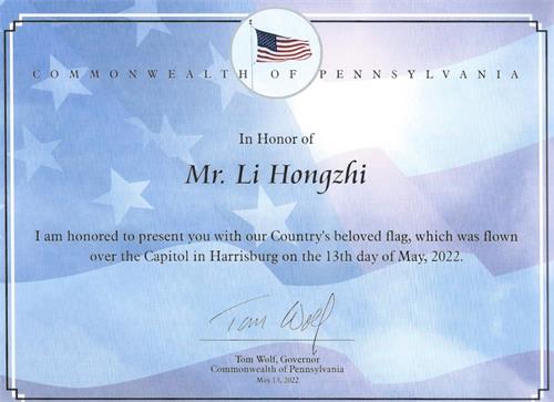 '图2：宾州州长汤姆·沃尔夫（Tom Wolf）颁发证书，将这面“五·一三”飘扬在宾州国会大厦的美国国旗赠送给李洪志先生。'
