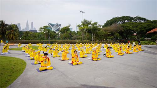 '图2~3:马来西亚部份法轮功学员在吉隆坡著名的休闲公园——蒂蒂旺沙湖滨公园(Titiwangsa Lake Garden)广场前进行集体炼功,场面庄严祥和。'