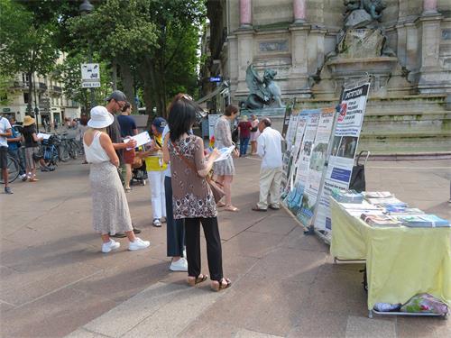 图9：二零二二年六月十九日，在巴黎圣米歇尔广场（Place Saint-Michel），人们观看展板，了解法轮功真相，签名支持制止迫害。
