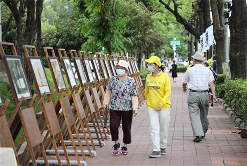 图3: 李姓学员陪着对大法有误解的老太太，边走边看展板，经过学员细心讲<span class='voca' kid='62'>真相</span>之后，老太太心中豁然开朗，解开心中的误解。