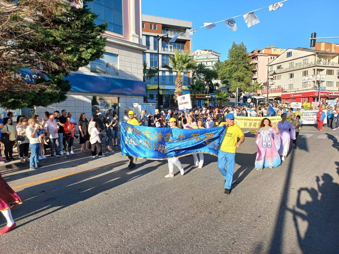 '图2：七月二十一日，土耳其法轮功学员参加“爱、友谊与和平”国际文化艺术节的游行，受到两旁观众的欢迎，他们有的跟学员招手，有的鼓掌喝彩。'