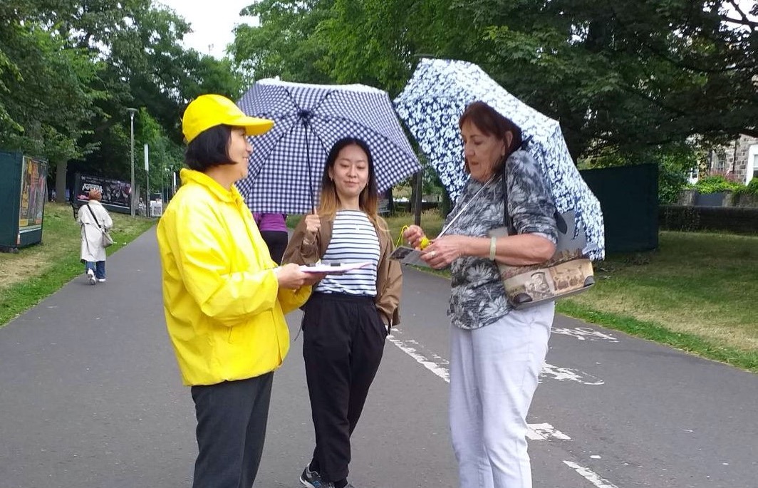 图7：两位打着雨伞的女士签名支持反迫害，还表示要学炼功法。