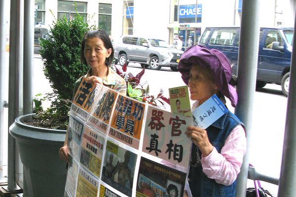 圖3：2015年7月15日，紐約曼哈頓帝國大廈門前，從大陸流亡海外的法輪功學員葛榮貞（左）和李敏（右）手舉真相展板。