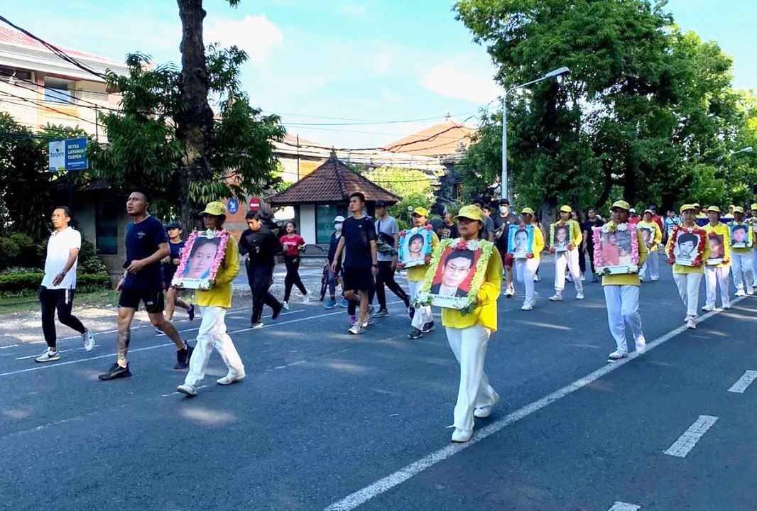'图4：行进间，峇里岛学员手持被中共迫害致死的中国法轮功学员的照片。'