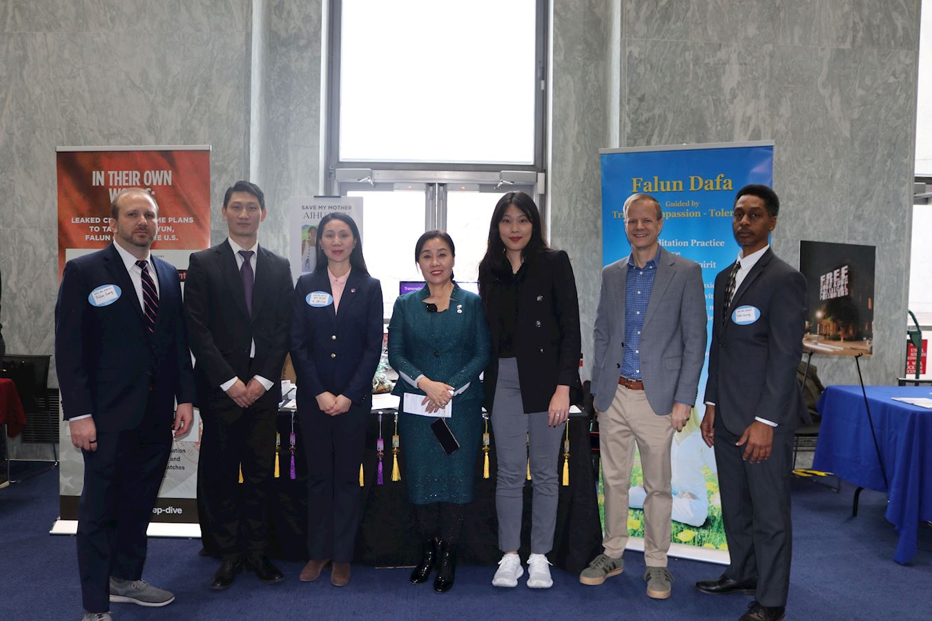 '图1:二零二五年十二月十日,法轮大法信息中心在美国国会主办人权展会,参观者在展位前与法轮功学员合影。'