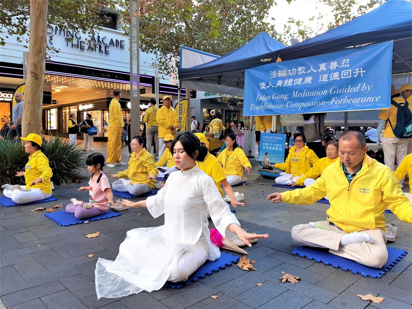 '图1~2:法轮功学员在展位前集体炼功,展示五套功法。'