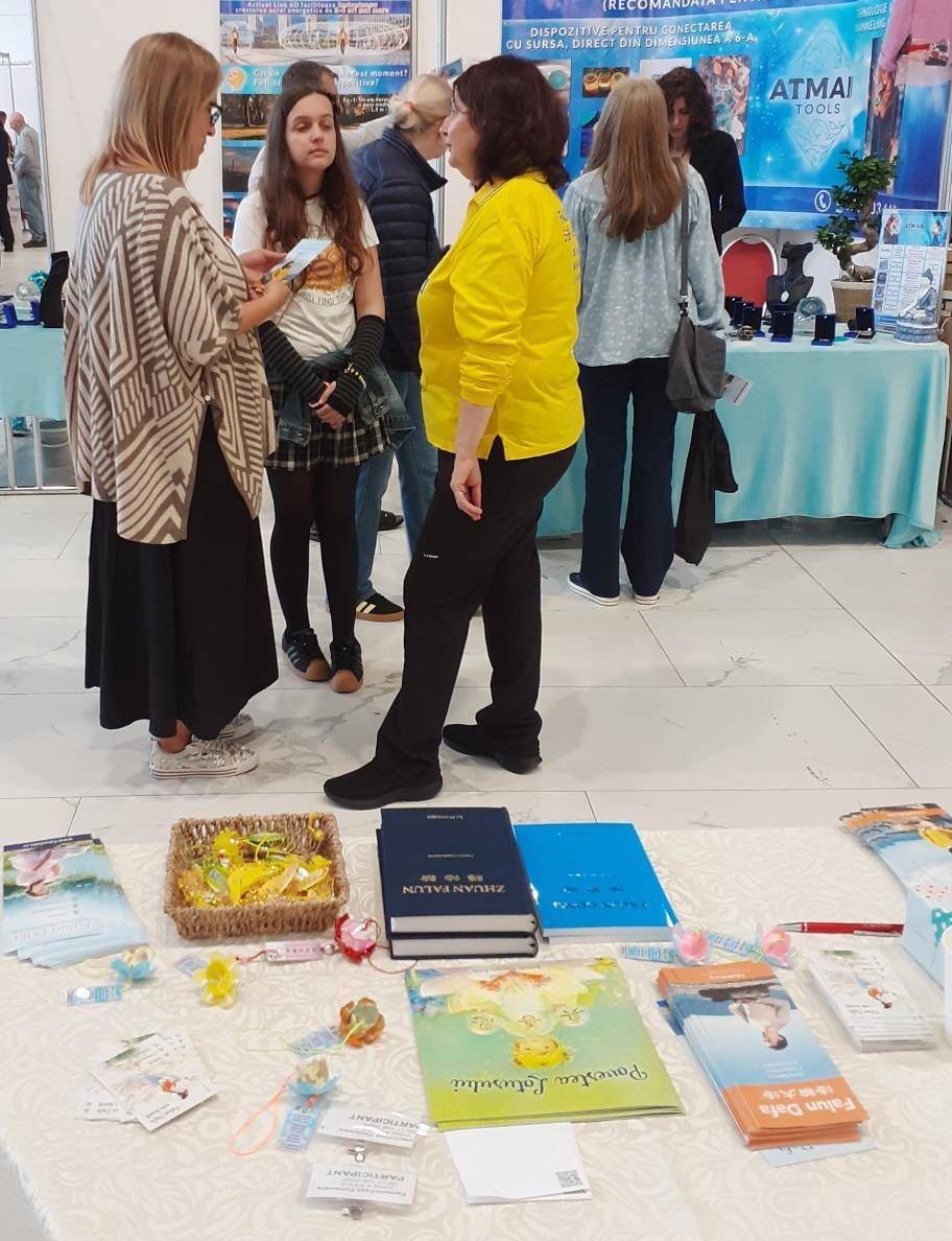 '图12:两名学生特意来到法轮功展位前试炼功法。'