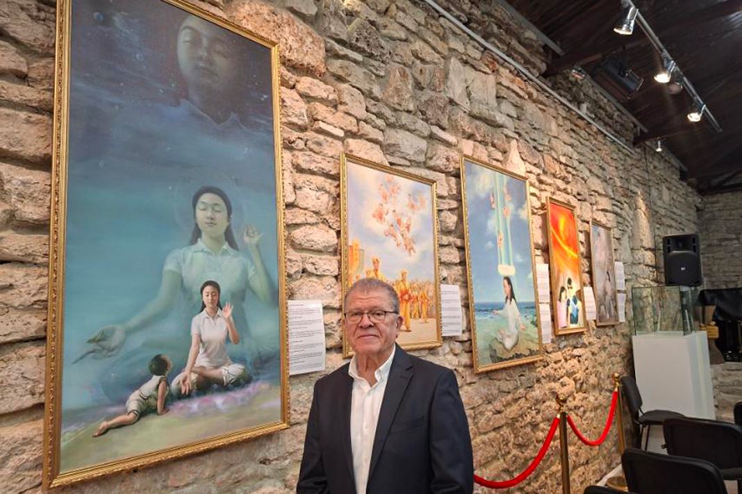 '图9:潘特列·潘特列耶夫在“真善忍美展”的一幅画作旁留影。(明慧网)'
