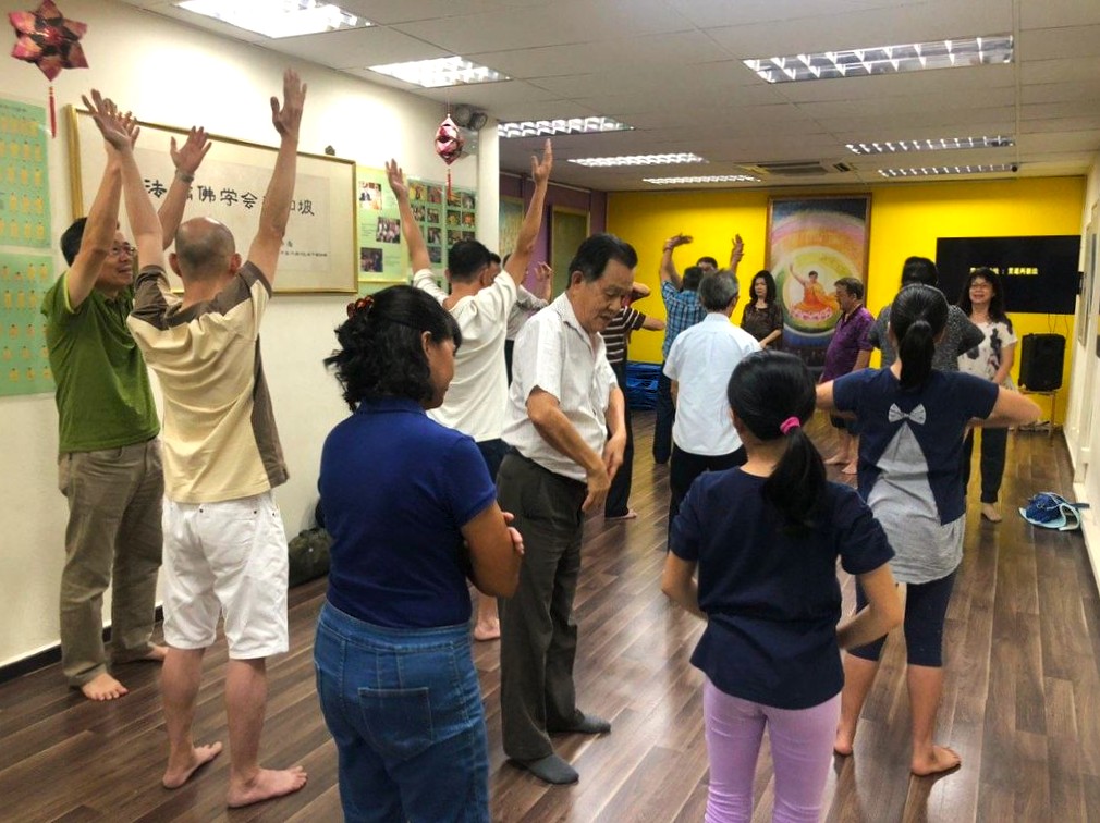 图2:二零一九年十二月二十八日至二零二零年一月五日,新加坡法轮佛学会举办九天免费学习班。图为老学员在教新学员炼功。(明慧网)