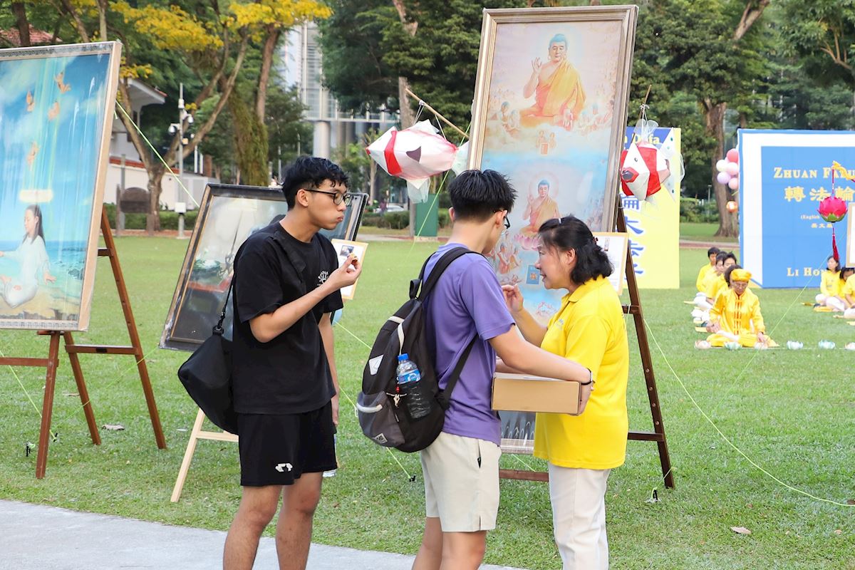 '图9:法轮功学员沈女士(右一)在芳林公园向过往民众介绍法轮功真相。(明慧网)'